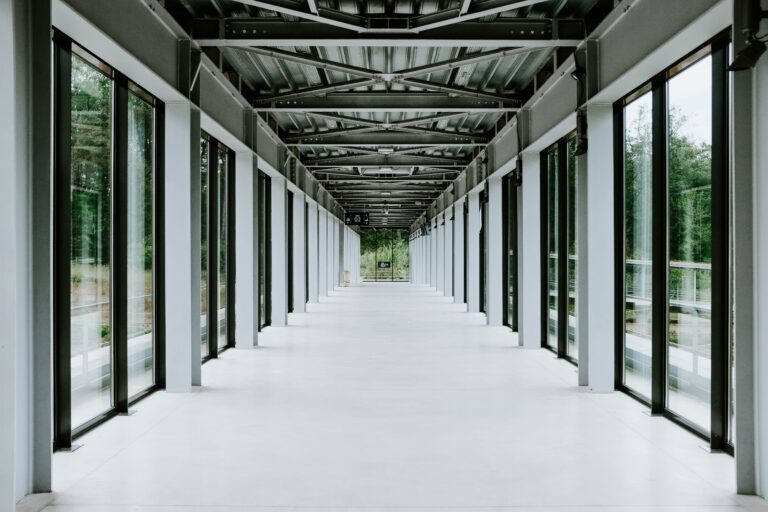 White hallway with glass doors and metal ceiling in a modern building